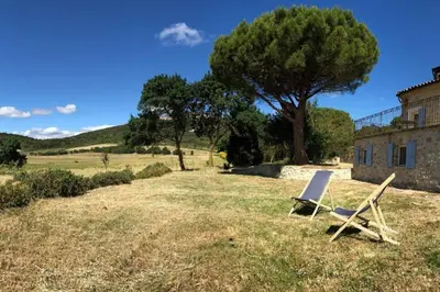 a chair sitting in the grass next to a house at Domaine de Roquenégade - Piscine, sauna et bain nordique in Pradelles-en-Val