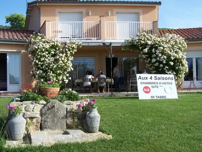 a dining room with a table and chairs and a television at Aux 4 Saisons in Tabre