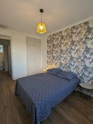 a bedroom with a bed with a blue bedspread on a wall at Appartment - vue imprenable sur la cité médiévale - Parking gratuit - Climatisé in Carcassonne