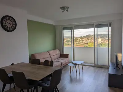 a living room with a table and a couch at Appartment - vue imprenable sur la cité médiévale - Parking gratuit - Climatisé in Carcassonne