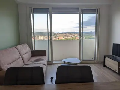 a living room with a couch and large windows at Appartment - vue imprenable sur la cité médiévale - Parking gratuit - Climatisé in Carcassonne