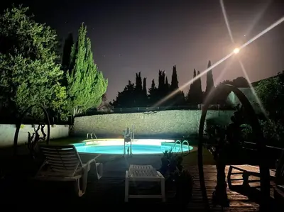 a swimming pool at night with two lawn chairs at Haut de maison et piscine dans un domaine viticole in Montbrun-des-Corbières