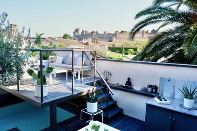 a balcony with a chair and plants on a building at La Maison Blanche 5*, Piscine & vue Cité Médiévale in Carcassonne