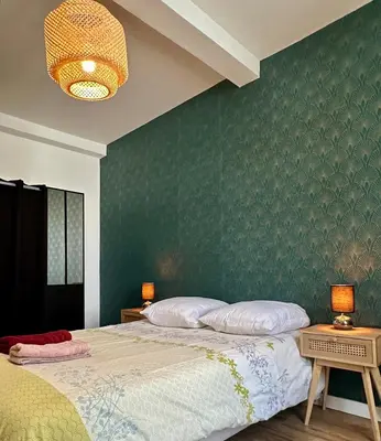 a bedroom with a bed and a green wall at Appartement Minervoise - Gare Carcassonne in Carcassonne