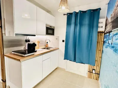 a kitchen with white cabinets and a blue shower curtain at BORA-BORA SUITE - Jacuzzi - Centre by Narbana in Narbonne