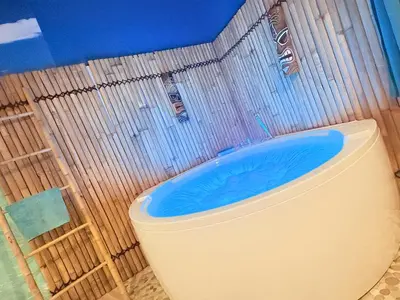 a bathroom with a toilet with a blue bath tub at BORA-BORA SUITE - Jacuzzi - Centre by Narbana in Narbonne