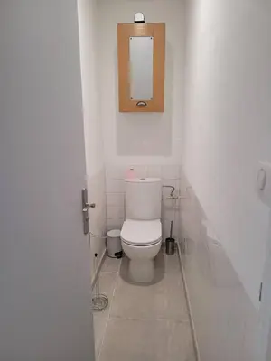 a white bathroom with a toilet and a mirror at Appartement Morgand in Narbonne