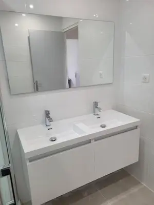 a white bathroom with two sinks and a mirror at Appartement Morgand in Narbonne