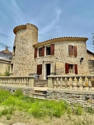 an old stone house with a stone fence in front of it at Le Petit Château de Tournissan in Tournissan
