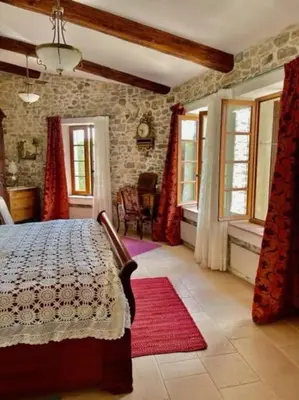 a bedroom with a bed and a stone wall at Le Petit Château de Tournissan in Tournissan
