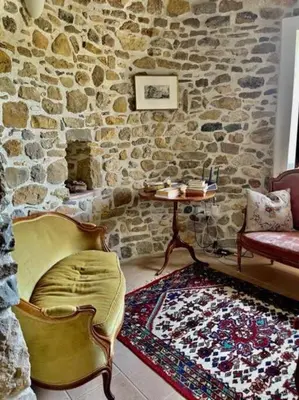 a room with a stone wall with a chair and a table at Le Petit Château de Tournissan in Tournissan