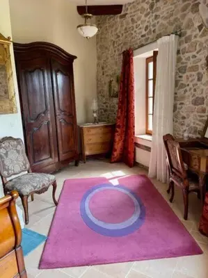 a living room with a pink rug on the floor at Le Petit Château de Tournissan in Tournissan