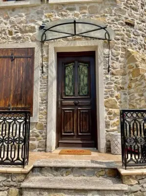 a wooden door on a stone building with two gates at Le Petit Château de Tournissan in Tournissan