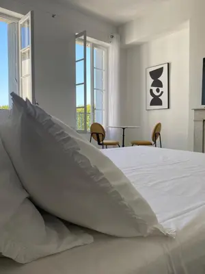 a white bed with a pillow on top of it at Maison d’hôtes Le 1853 in Narbonne