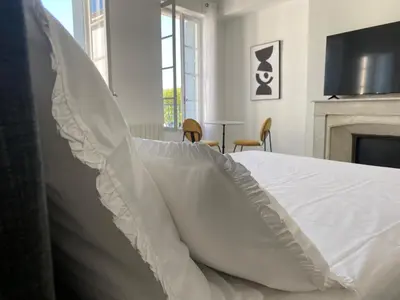 a bedroom with a white bed and a fireplace at Maison d’hôtes Le 1853 in Narbonne