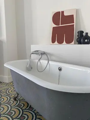 a bath tub in a bathroom with a painting on the wall at Maison d’hôtes Le 1853 in Narbonne