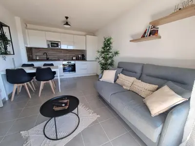a living room with a gray couch and a table at L'Appartement Ensoleillé, WIFI-Clim-Gare-Terrasse in Narbonne