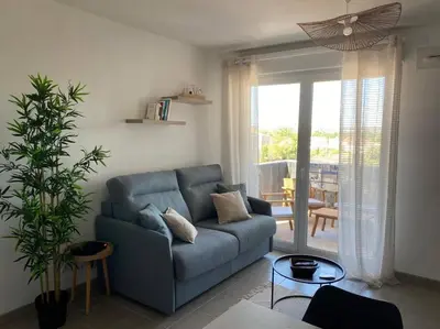 a living room with a blue couch and a table at L'Appartement Ensoleillé, WIFI-Clim-Gare-Terrasse in Narbonne