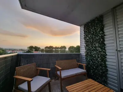 two chairs on a balcony with a green wall at L'Appartement Ensoleillé, WIFI-Clim-Gare-Terrasse in Narbonne