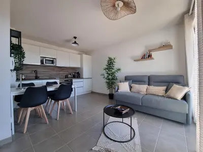a living room with a couch and a kitchen at L'Appartement Ensoleillé, WIFI-Clim-Gare-Terrasse in Narbonne