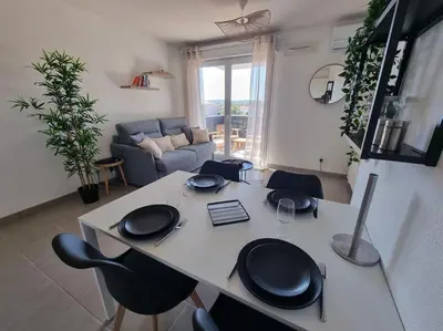a kitchen and living room with a table and chairs at L'Appartement Ensoleillé, WIFI-Clim-Gare-Terrasse in Narbonne