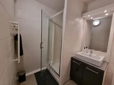 a bathroom with a glass shower and a sink at L'Appartement Ensoleillé, WIFI-Clim-Gare-Terrasse in Narbonne