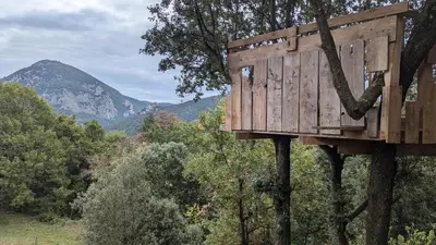 a wooden tree house hanging from a tree at Grande maison Carpediem, le calme à la campagne in Cassaignes