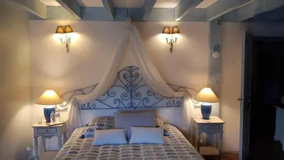 a bedroom with a white bed with two night stands at La Demeure du Pressoir in Cuxac-dʼAude