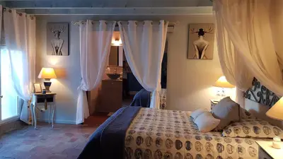 a bedroom with a bed and two lamps and curtains at La Demeure du Pressoir in Cuxac-dʼAude