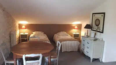 a bedroom with two beds and a table and a dresser at La Demeure du Pressoir in Cuxac-dʼAude