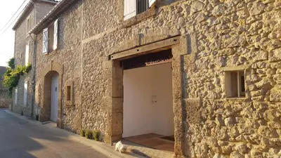 a stone building with a white garage door at La Demeure du Pressoir in Cuxac-dʼAude