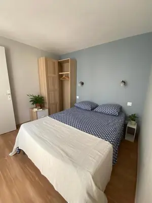 a bedroom with a large bed with a blue blanket at La Maison de Jeanne in Narbonne