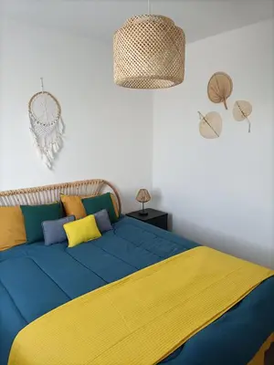 a bed with a blue and yellow blanket on it at L'hippocampe in Gruissan