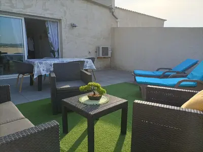 a patio with chairs and a table with a plant on it at L'hippocampe in Gruissan
