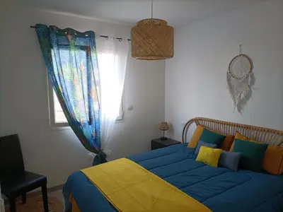 a bedroom with a blue and yellow bed and a window at L'hippocampe in Gruissan