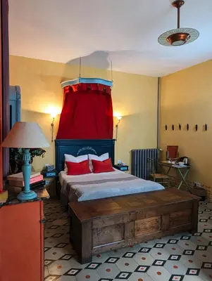 a bedroom with a bed with a red curtain at Les Chambres des Dames in Rieux-Minervois
