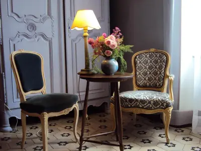 two chairs and a table with a vase of flowers and a lamp at Les Chambres des Dames in Rieux-Minervois
