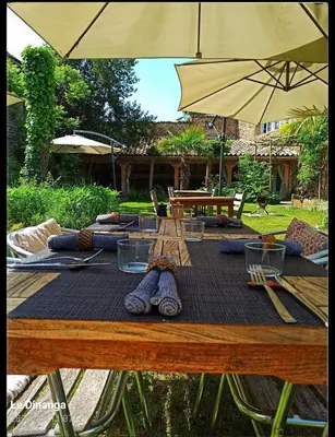 a wooden table with an umbrella and some ties on it at LE DINANGA in Léran