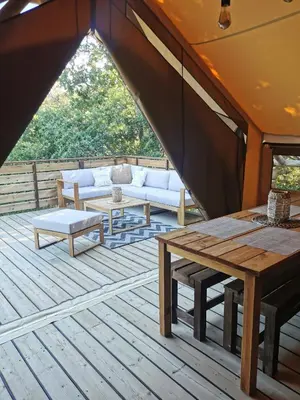 a patio with a couch and tables on a deck at Le lodge cocooning in Ansignan