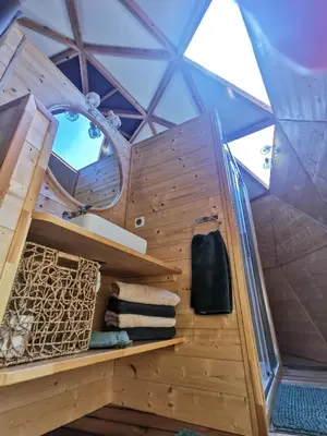 a room in a dome with wooden shelves and towels at Le dôme géodésique in Ansignan