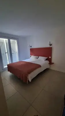 a bedroom with a large bed with a red headboard at Appartement calme centre ville à 80m des Halles in Narbonne