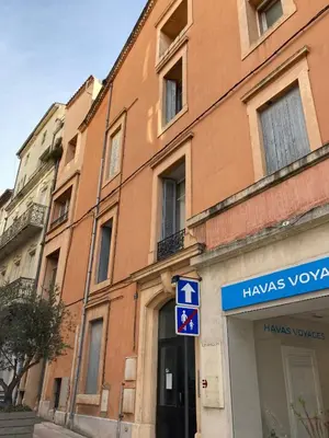 a building with a blue sign in front of it at Cours République in Narbonne