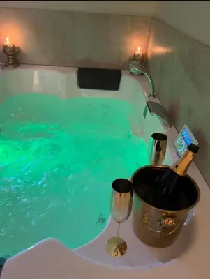 a bath tub filled with blue water next to a sink at La Halte Louis XIII in Bram