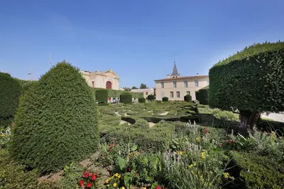 a garden with bushes and flowers in front of a building at Le Barral in Castres