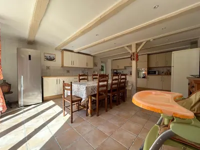 a kitchen with a table and chairs and a refrigerator at VILLA AU CALME AVEC PISCINE in Moussan