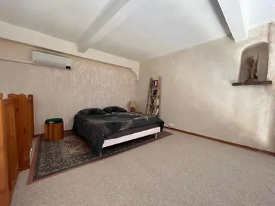 a bedroom with a bed in the corner of a room at VILLA AU CALME AVEC PISCINE in Moussan