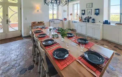 a long wooden table with plates and wine glasses at 5 Bedroom Beautiful Home In Ouveillan in Ouveillan