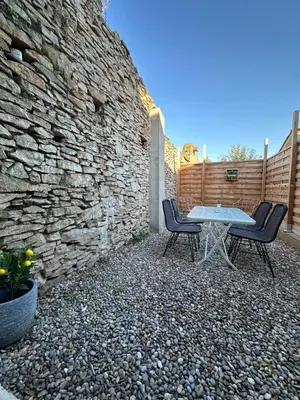 a patio with a table and two chairs in front of a wall at Maison cosy rénovée, proche de Carcassonne in Villarzel-Cabardès