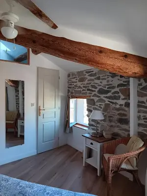 a room with a stone wall and a desk and a window at La Petite Romance - Gîte 3 étoiles in Siran