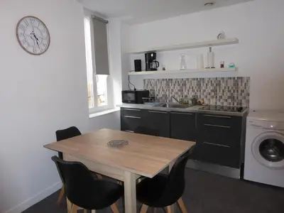 a kitchen with a wooden table and a washing machine at T1 Bis - Centre Historique de Narbonne in Narbonne